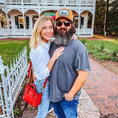 Jules Robertson is holding Jep Robertson close to him as they are standing Infront of Gruene Mansion building.